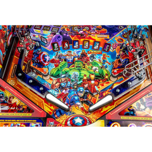 Close-up of a colorful Avengers-themed pinball machine playfield with illustrated superhero characters, score circles, flipper arms, and bright multicolor graphics.